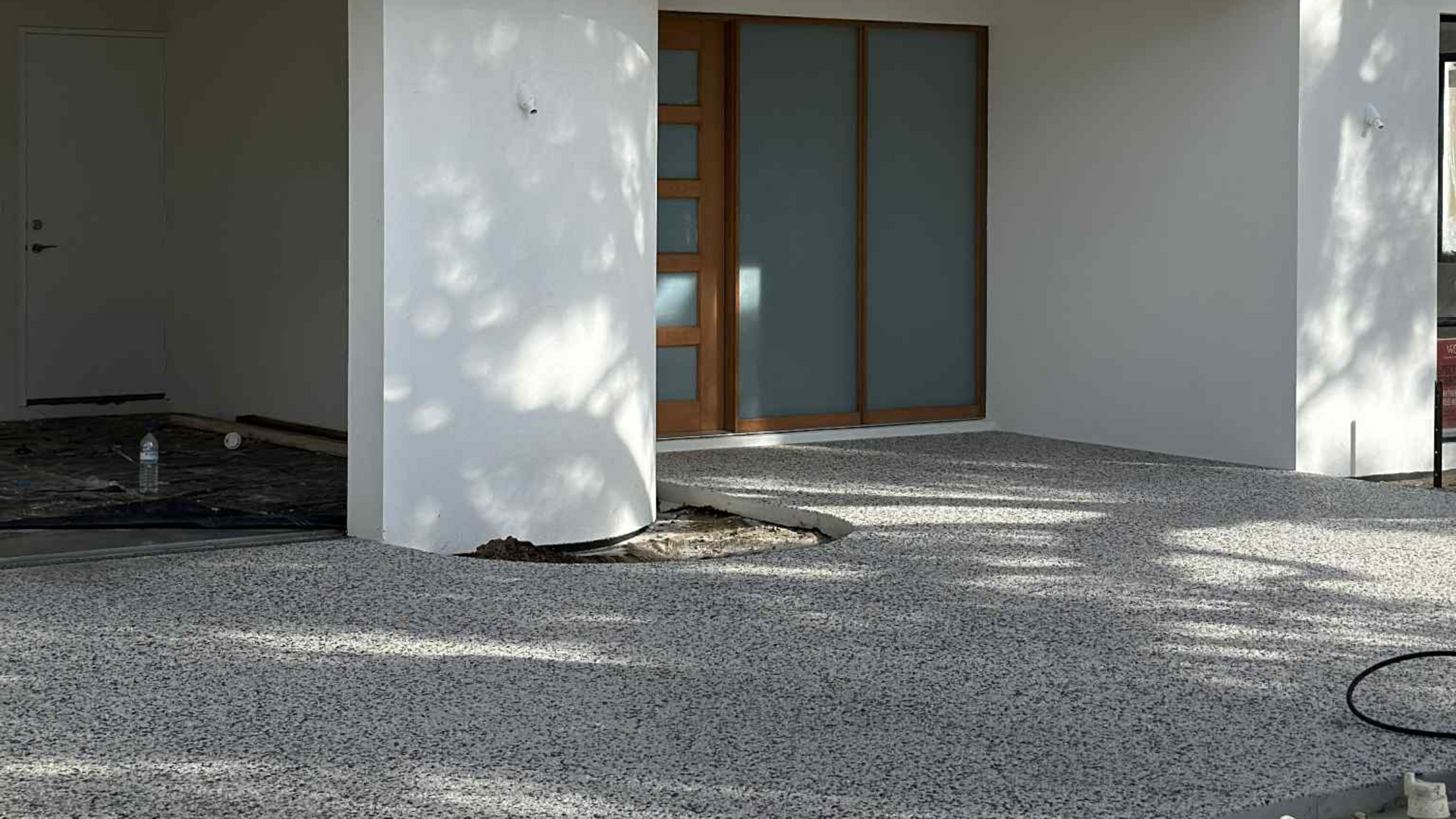 Kajani mix exposed aggregate driveway and house entrance with curved garden bed.