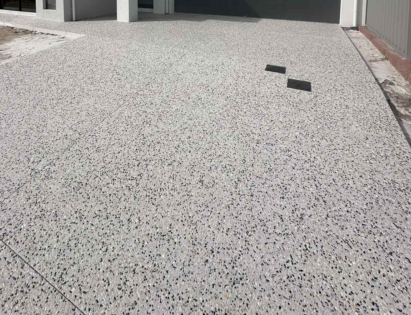 Exposed aggregate concrete driveway with integrated drainage for new home build in Perth Northern Suburbs.