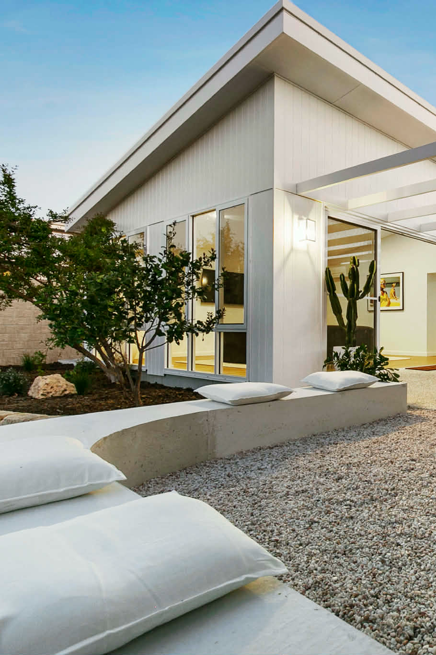 Modern white house with concrete bench seat around outdoor seating area.