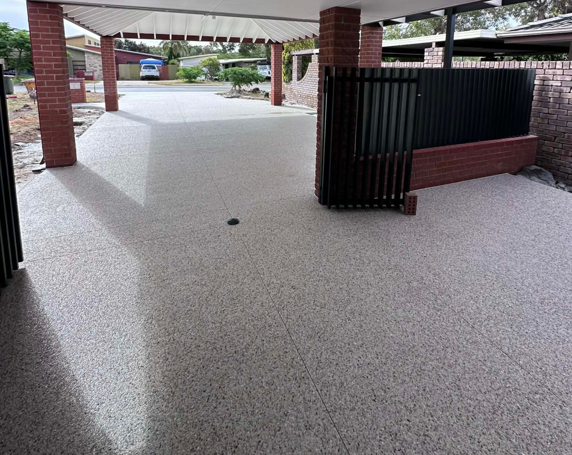 Eucalyptus white exposed aggregate driveway and patio area with black fence and red bricks.