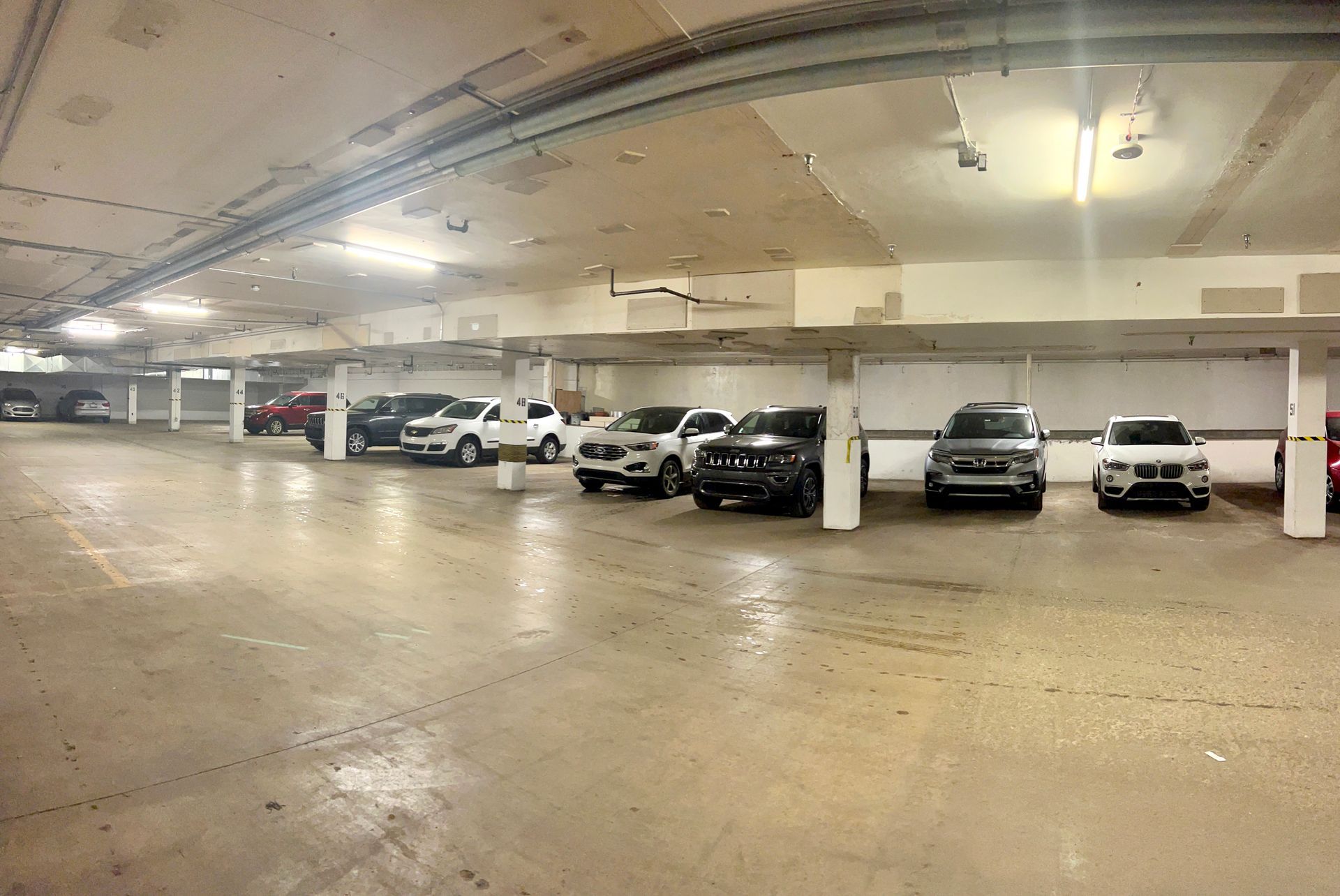 A parking garage filled with cars parked in a row.
