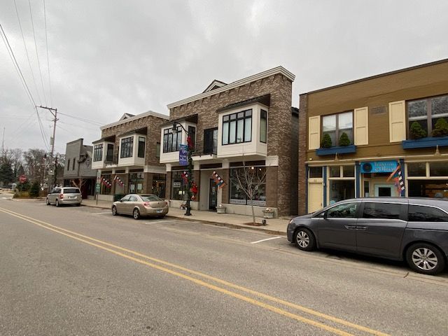 A row of buildings on a city street with cars parked in front of them.