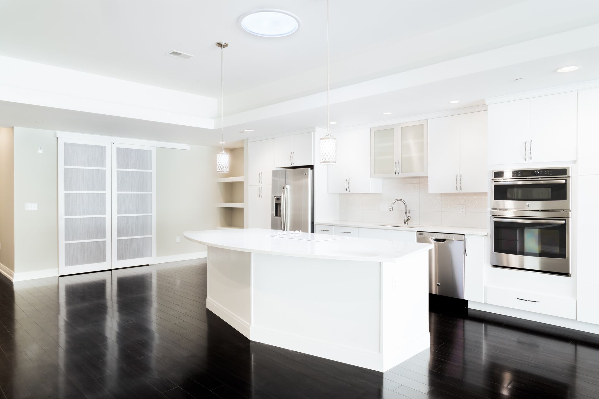 An empty kitchen with white cabinets and stainless steel appliances