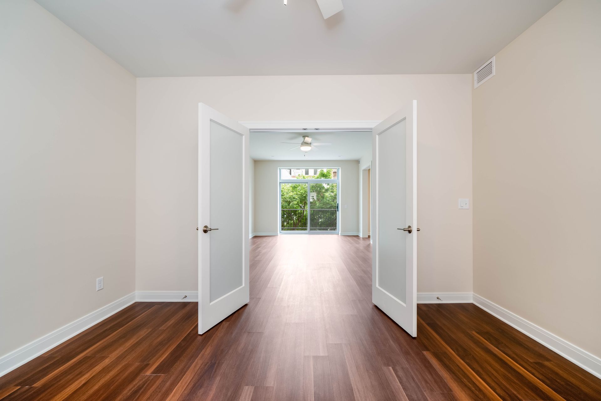 An empty room with hardwood floors and white walls.