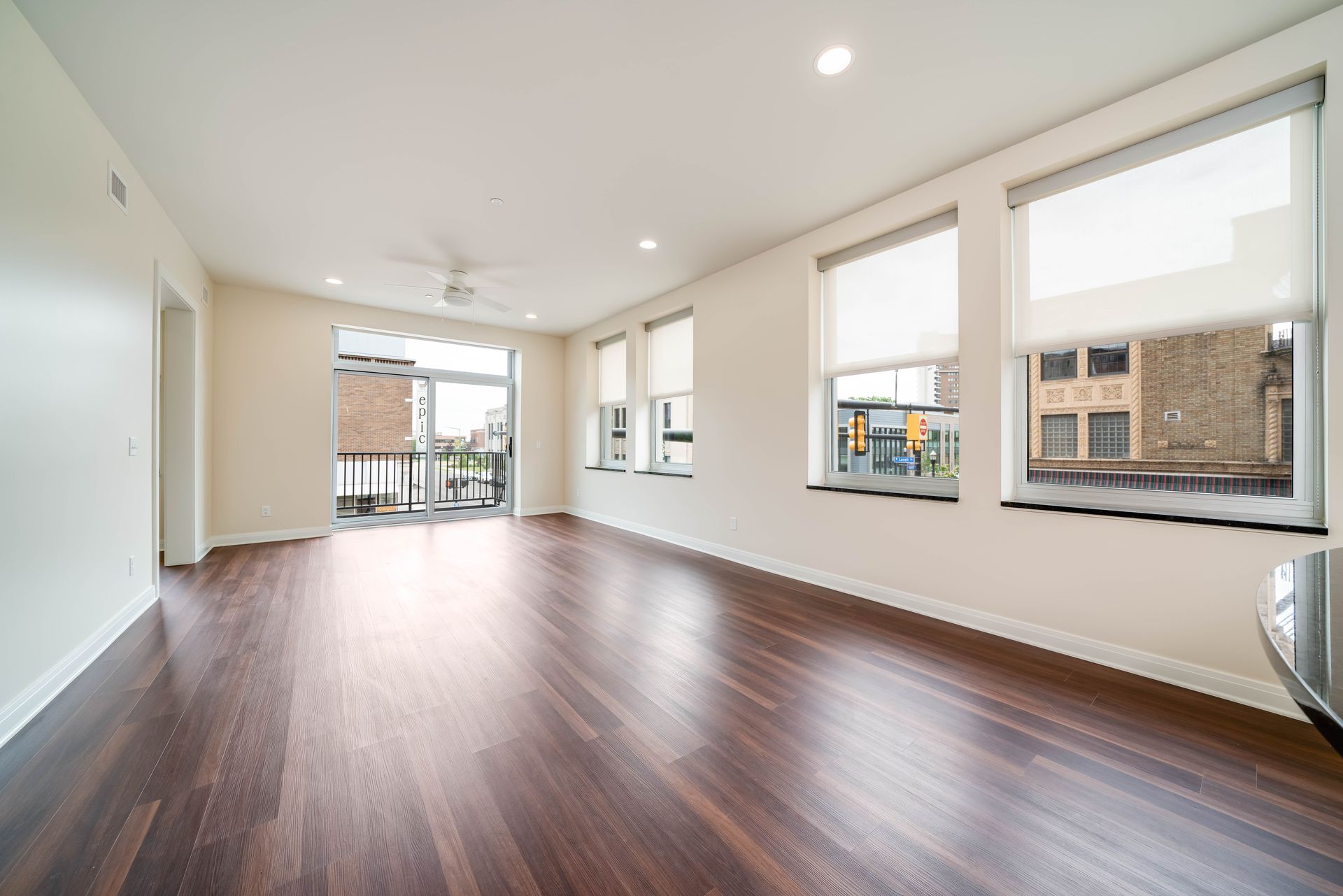 An empty living room with hardwood floors and lots of windows.