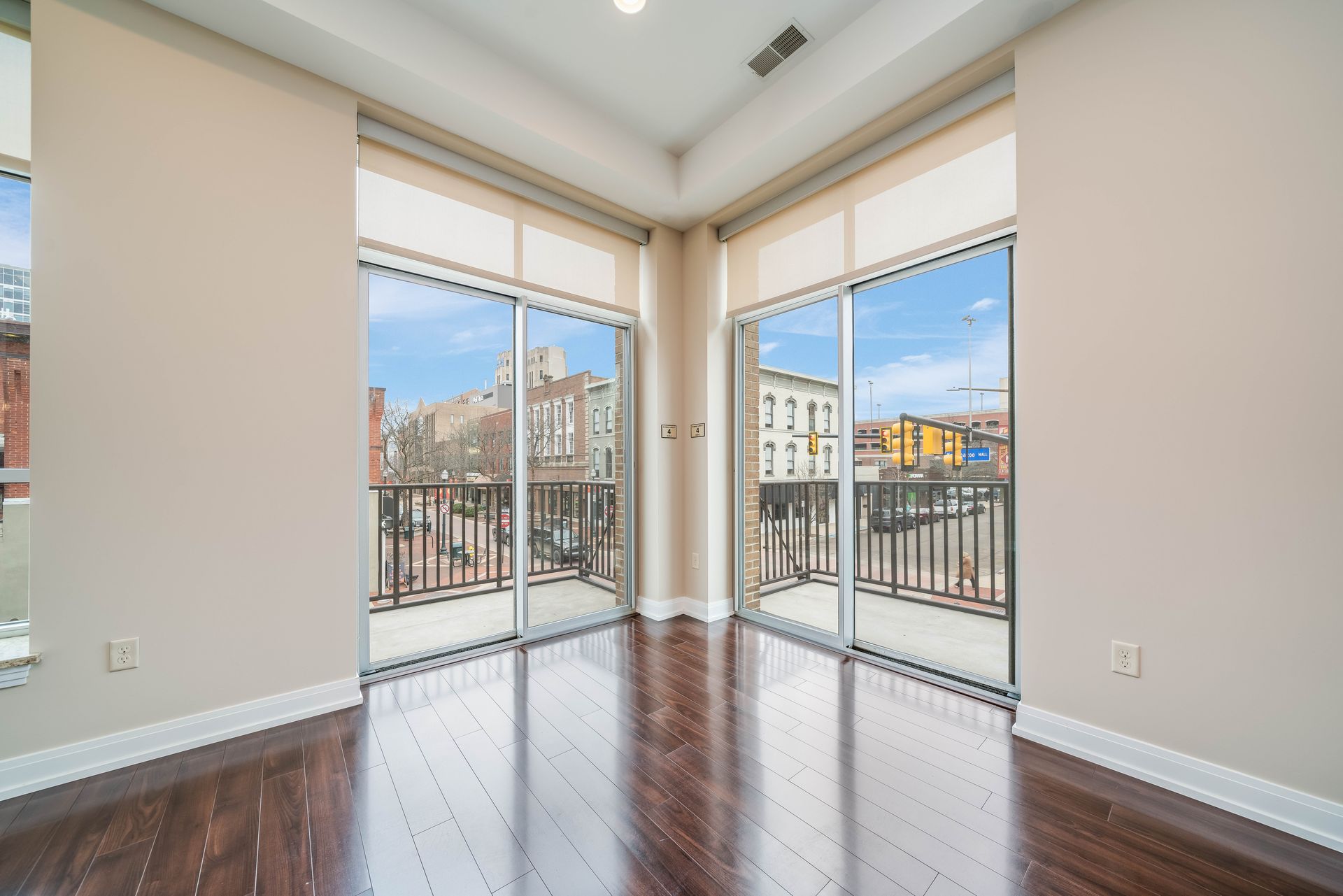 An empty living room with hardwood floors and sliding glass doors leading to a balcony.