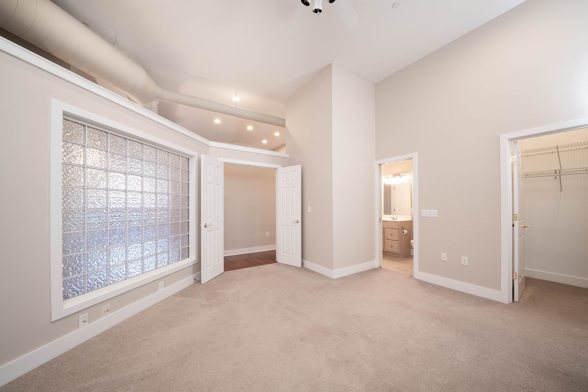 An empty bedroom with a large window and a walk in closet.