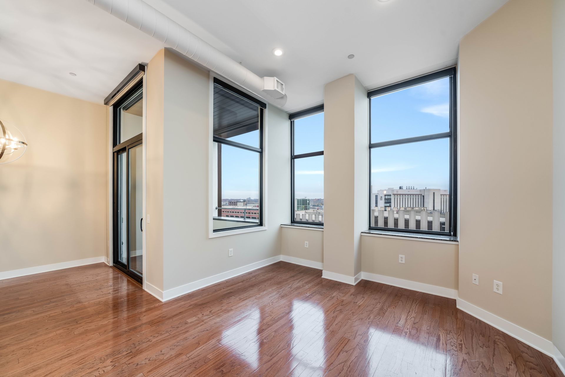 An empty living room with hardwood floors and large windows