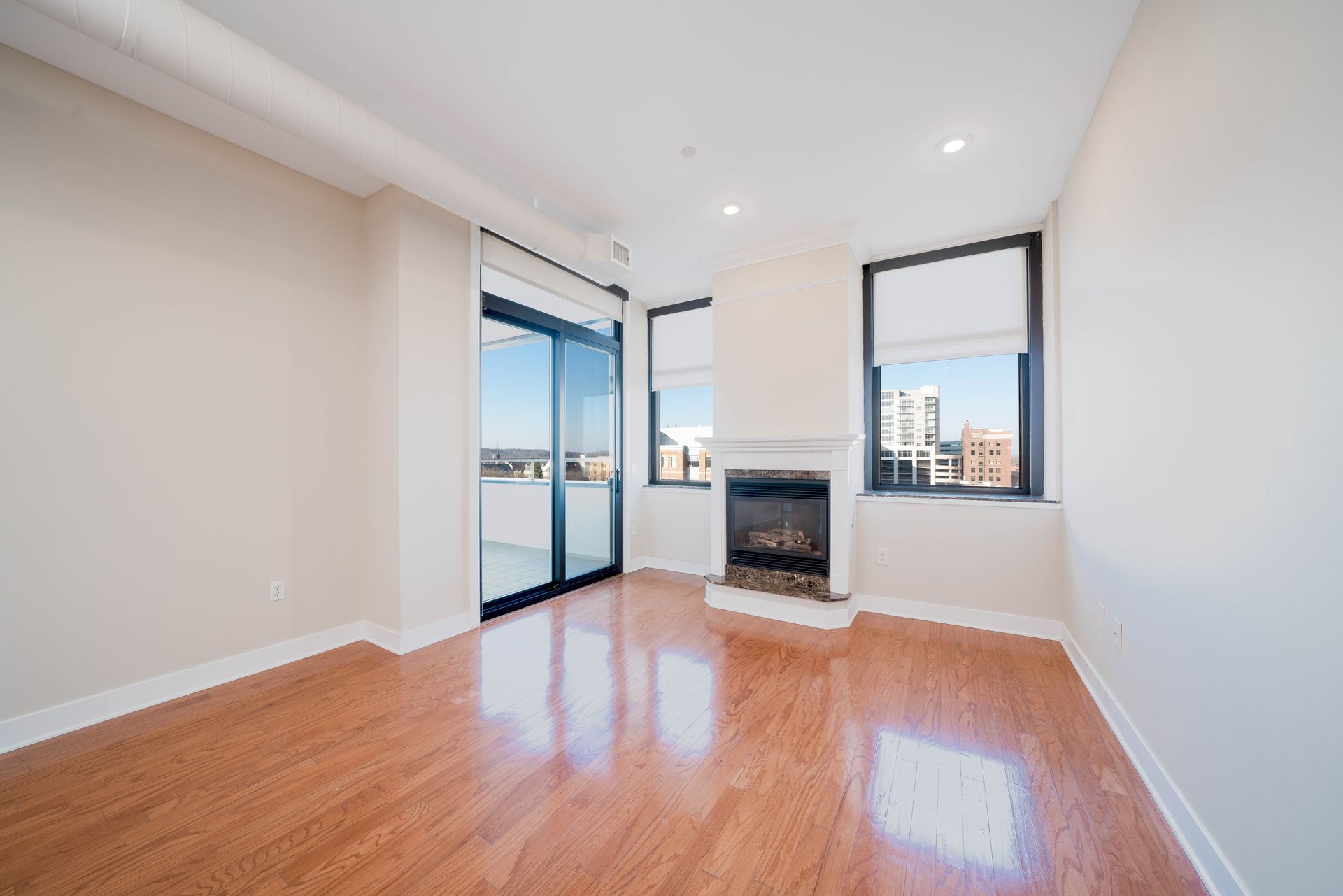 An empty living room with hardwood floors and a fireplace.