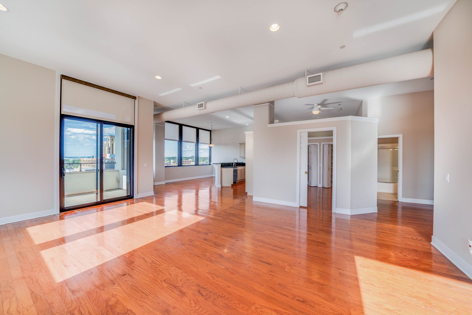 A large empty room with hardwood floors and sliding glass doors.