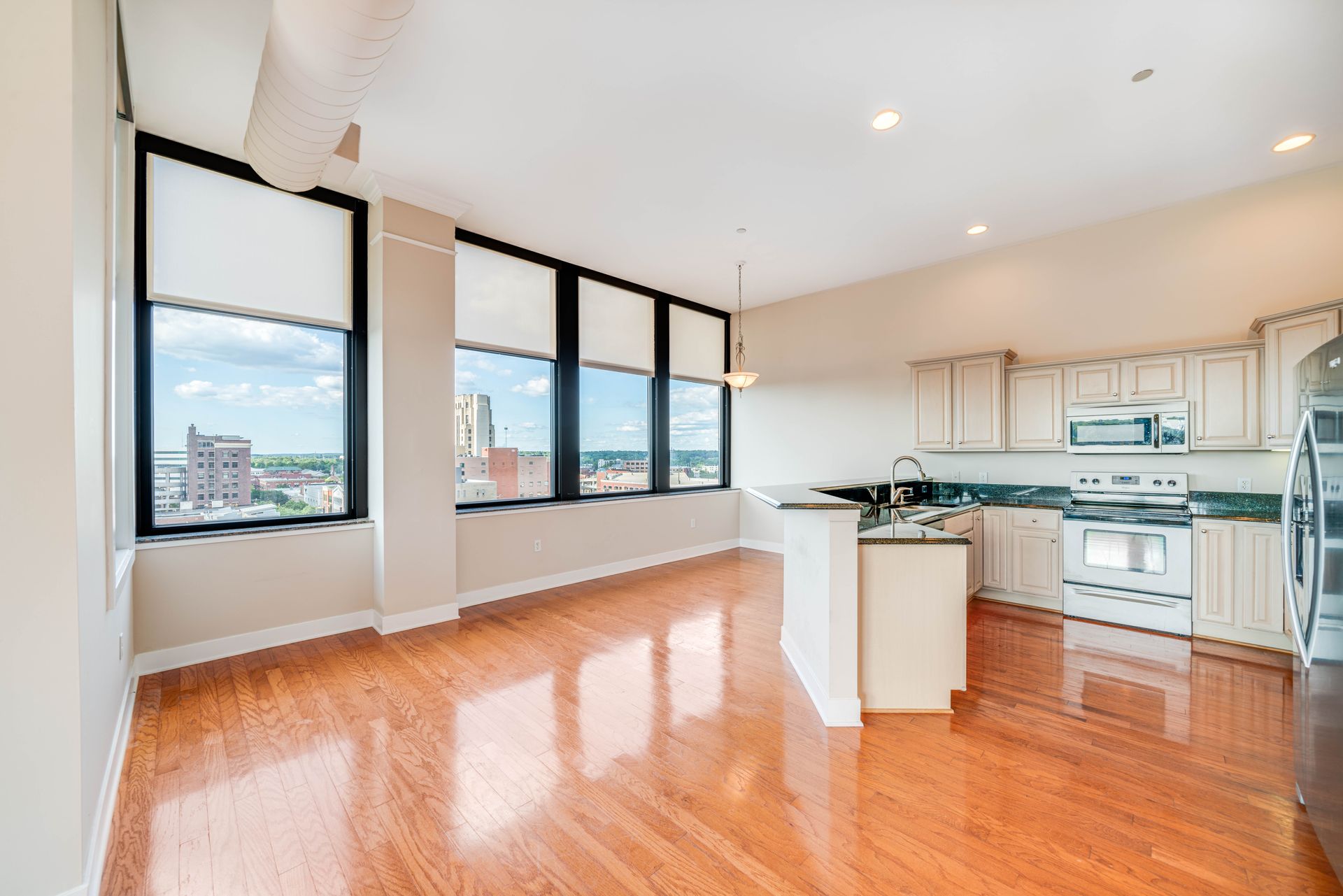 An empty kitchen with hardwood floors and stainless steel appliances