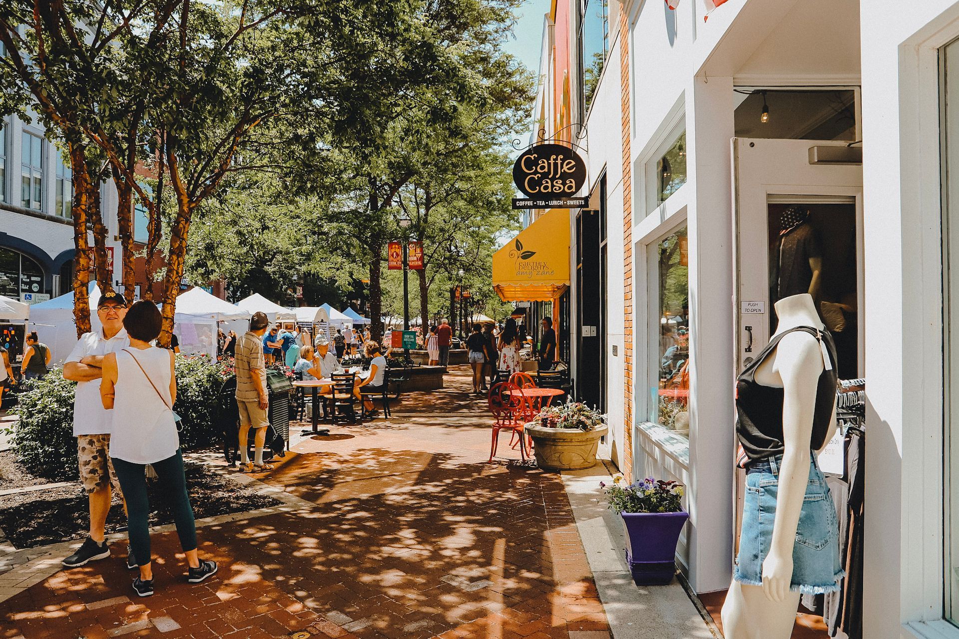A group of people are walking down a sidewalk in front of a store.