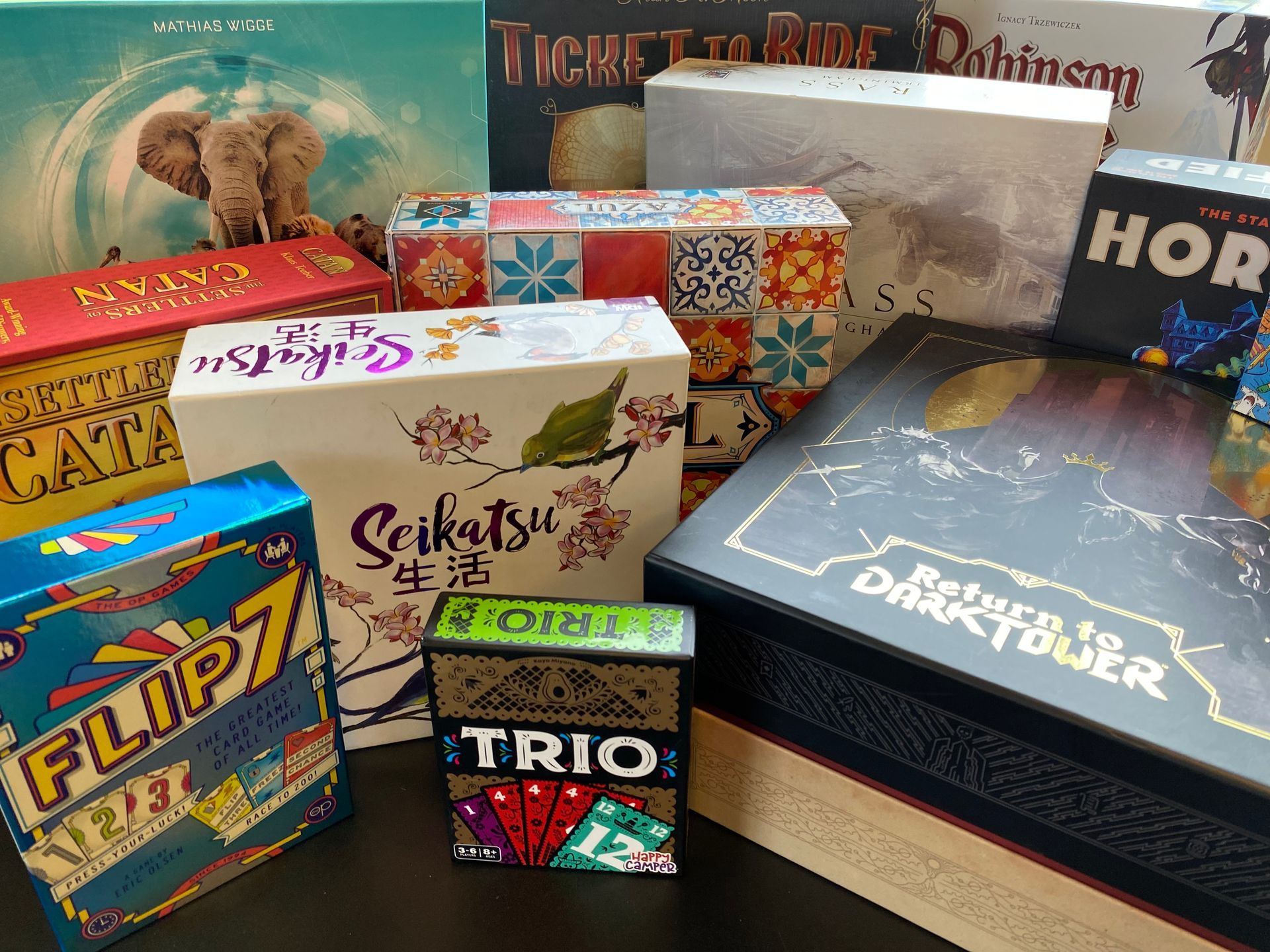 A collection of board game boxes, various sizes and designs, arranged on a surface.