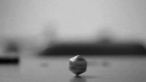 Animated GIF: a D20 spinning endlessly on a tabletop
