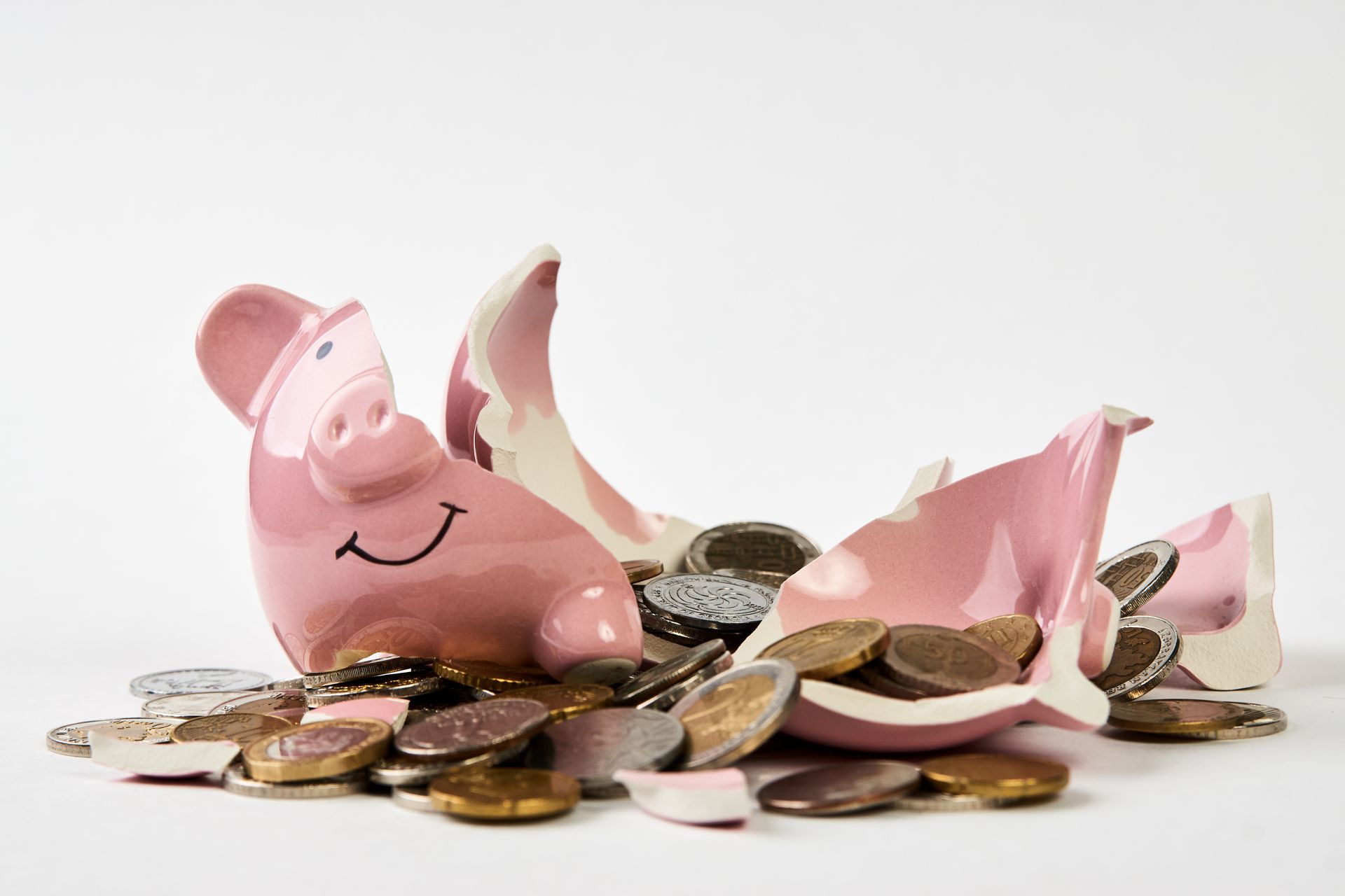 Broken pink piggy bank with coins spilling out.
