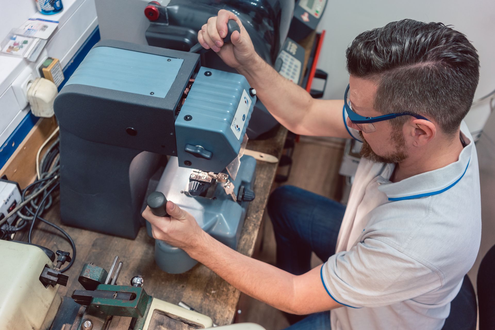 A locksmith key-making machine, focused on his task, with tools arranged on a table A locksmith key-making machine, focused on his task, with tools arranged on a table
