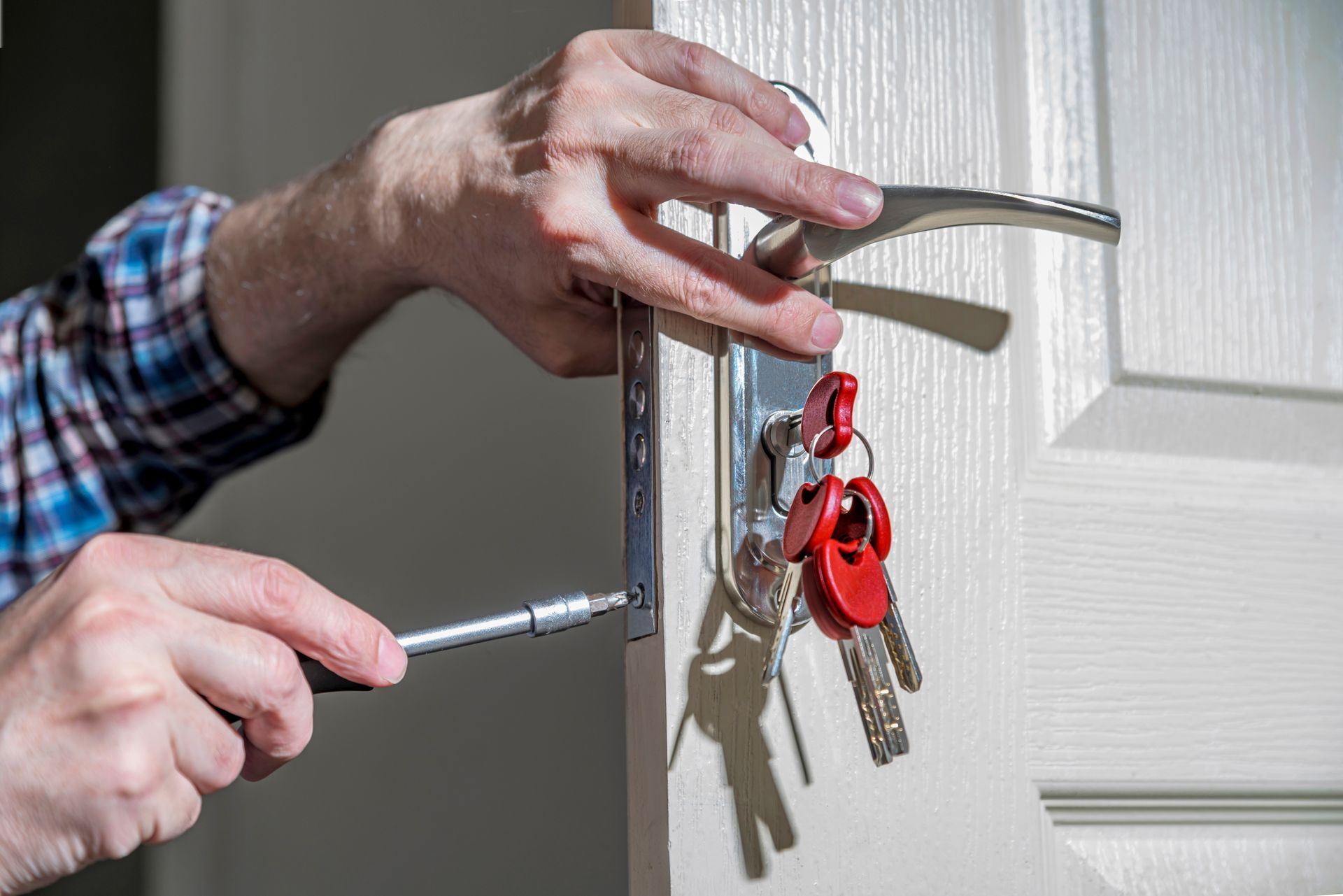 A locksmith is using a key to unlock and open a door, with a collection of keys A locksmith is using a key to unlock and open a door, with a collection of keys