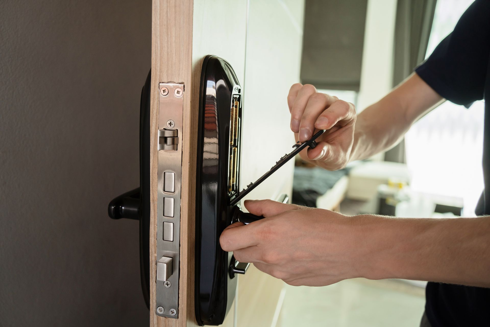 A locksmith repairs a door handle using a screwdriver, focused on the task at hand