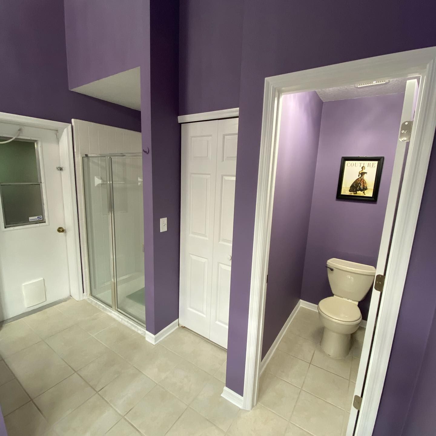 Purple bathroom with white doors, tiled floor, mirror closet, and a toilet in a small alcove.