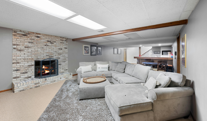 Cozy living room with fireplace, gray sectional sofa, and exposed beam ceiling.