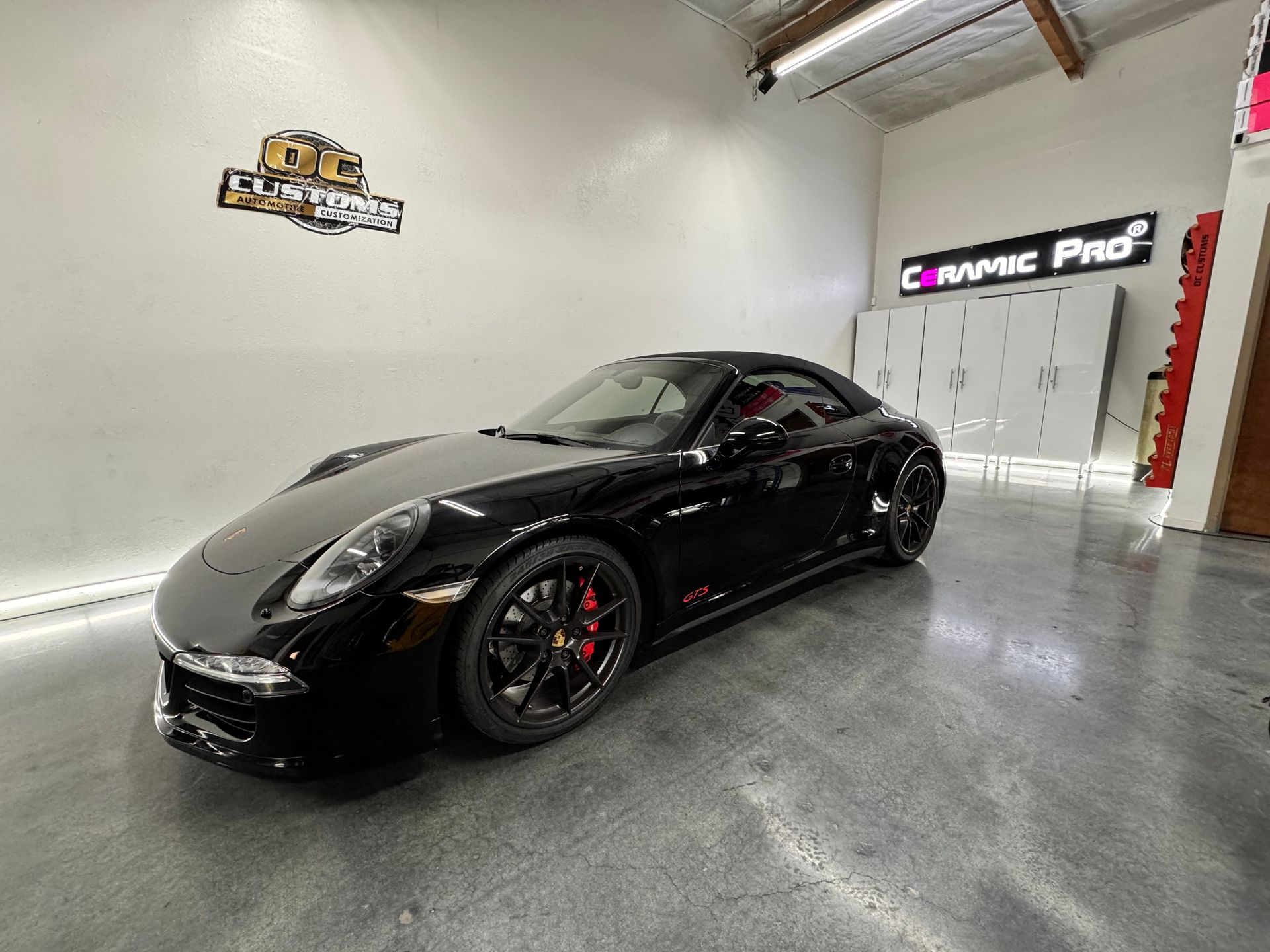 Black sports car in a garage showroom with polished concrete floor and white walls