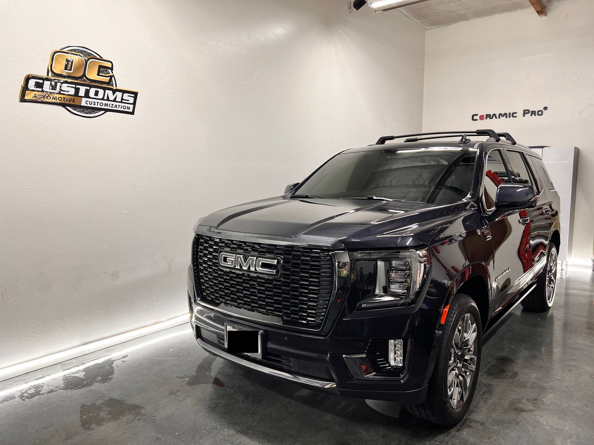 Black GMC SUV in a showroom with a white wall and glossy floor