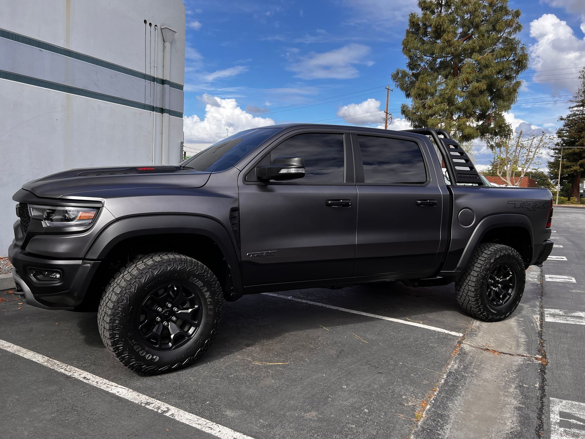 Black lifted pickup truck parked in a lot beside a building under a blue sky