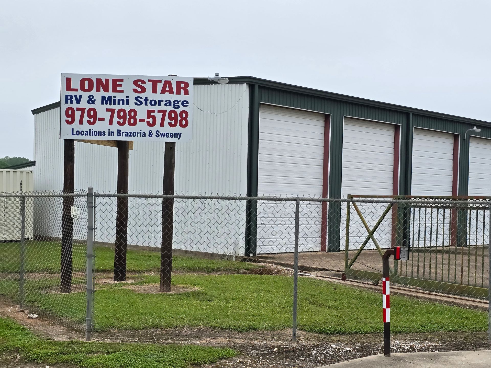 Lone Star RV & Mini Storage building behind a chain-link fence, with white roll-up doors and a sign.
