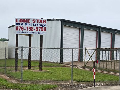 Lone Star RV & Mini Storage building behind a chain-link fence, with white roll-up doors and a sign.