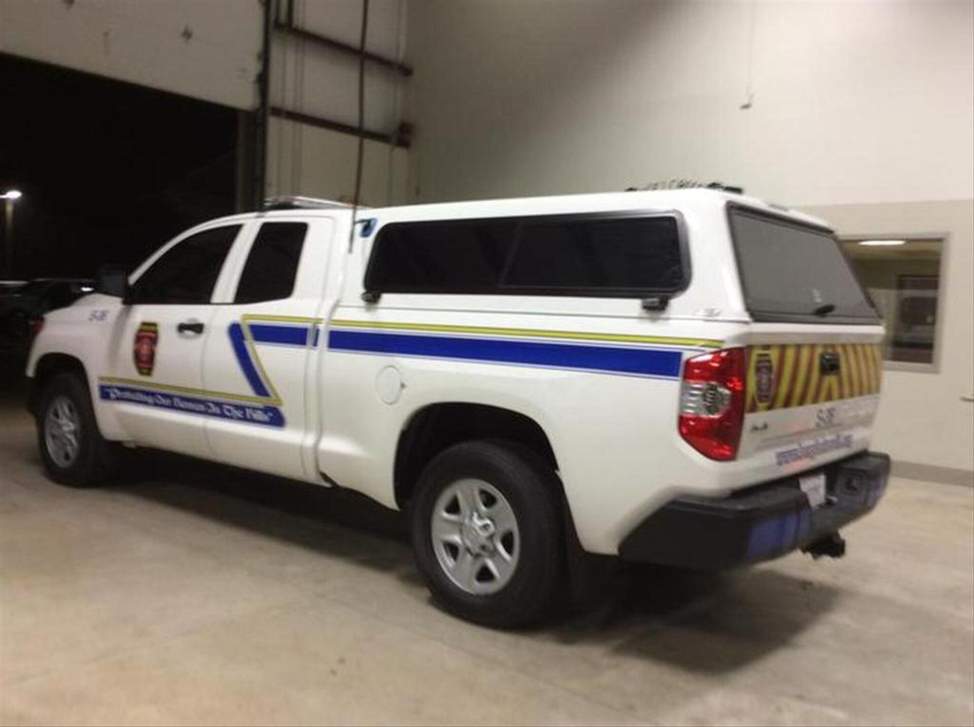A white and blue Bergheim VFD command truck is parked in a fire station.