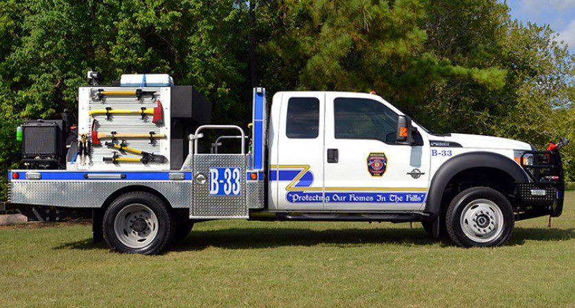 A white and blue Bergheim VFD fire truck with the number b38 on the side is parked in a grassy field.