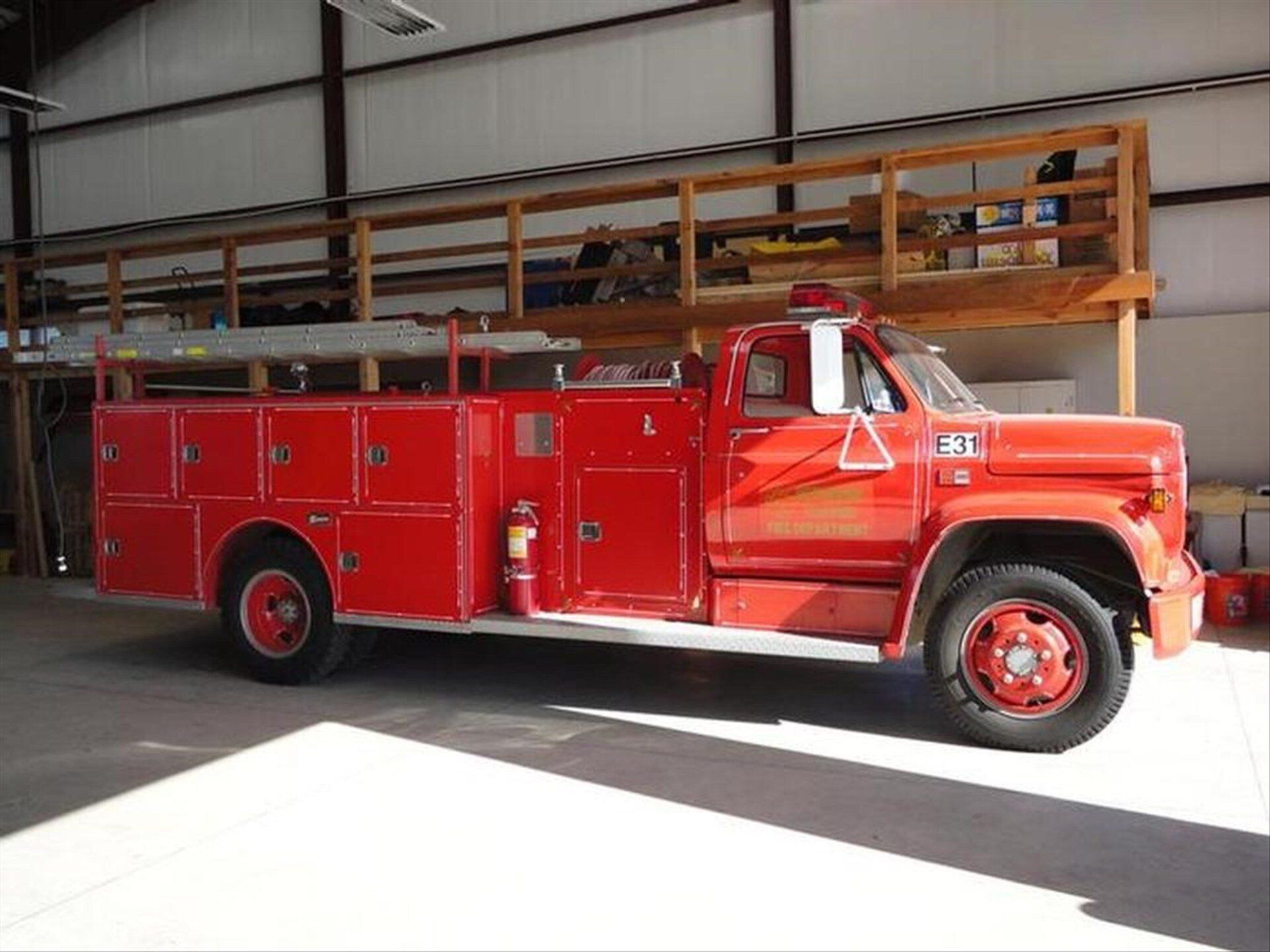An antique fire truck is parked in a fire station bay.