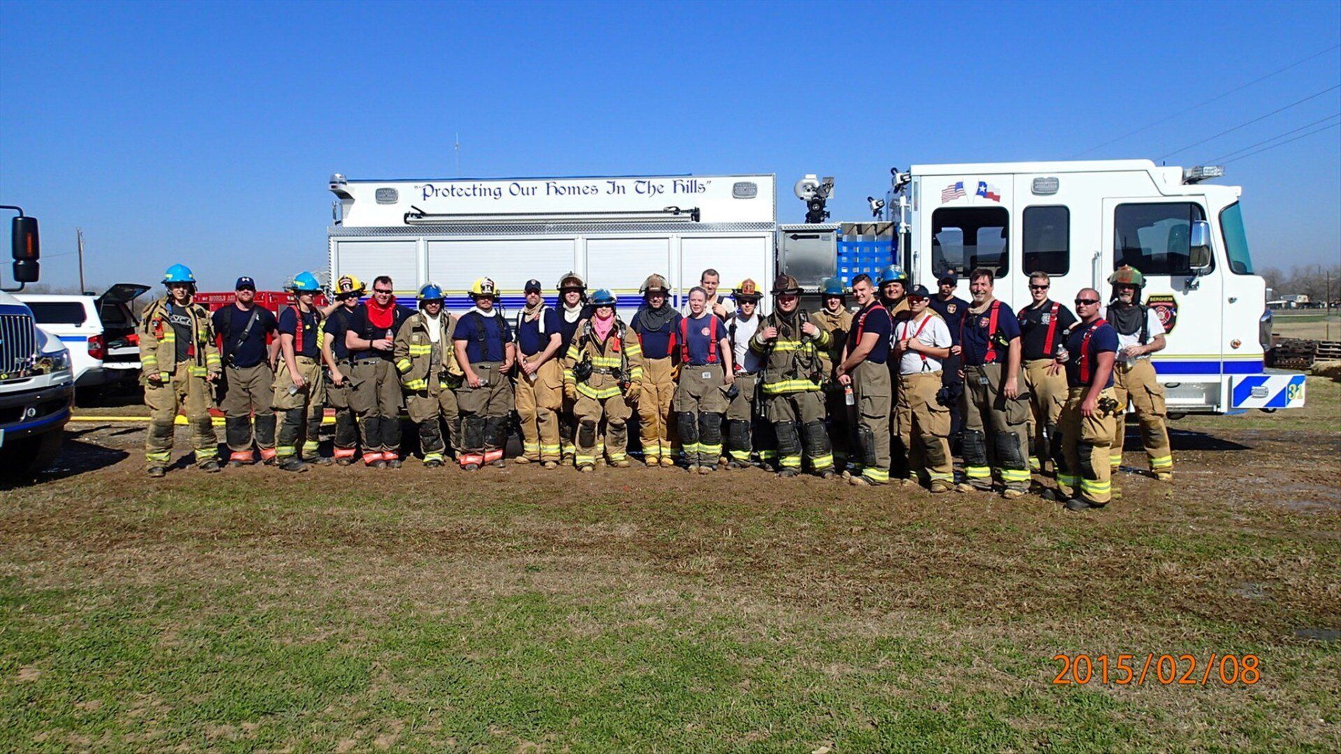 A group of firefighters are posing for a picture in front of a fire truck.