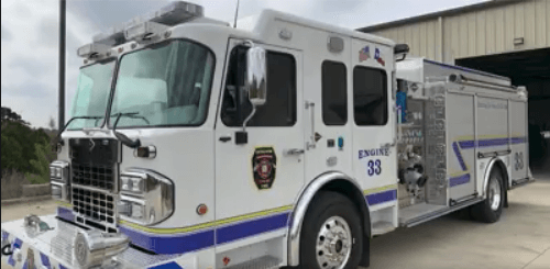 A white and blue Bergheim VFD fire truck parked in front of a fire station.