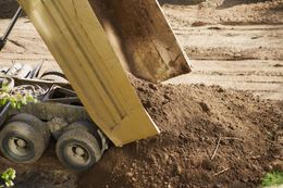 Yellow dump truck unloading dirt at a construction site