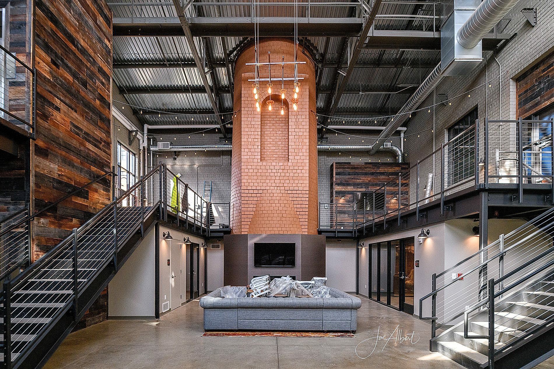 Interior of modern industrial building with copper chimney and steel staircases.