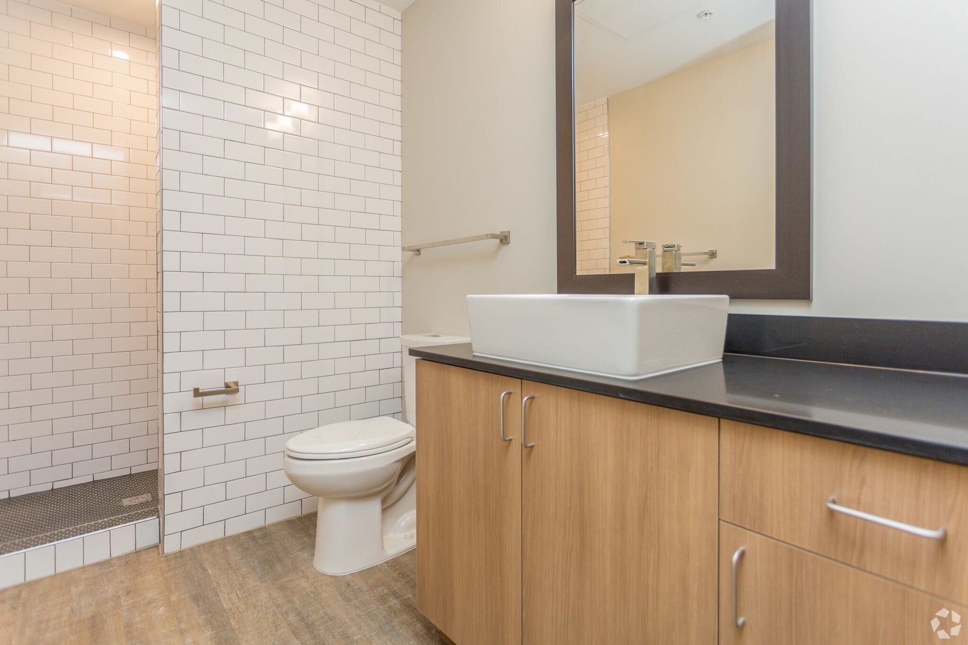 Modern bathroom with a white sink, wood cabinets, and white brick shower.