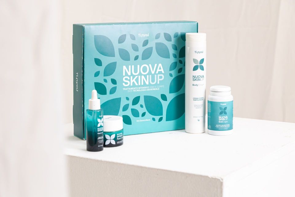 Apri la confezione regalo color verde acqua contenente prodotti per la cura della pelle, tra cui flaconi, vasetto e tubetto.