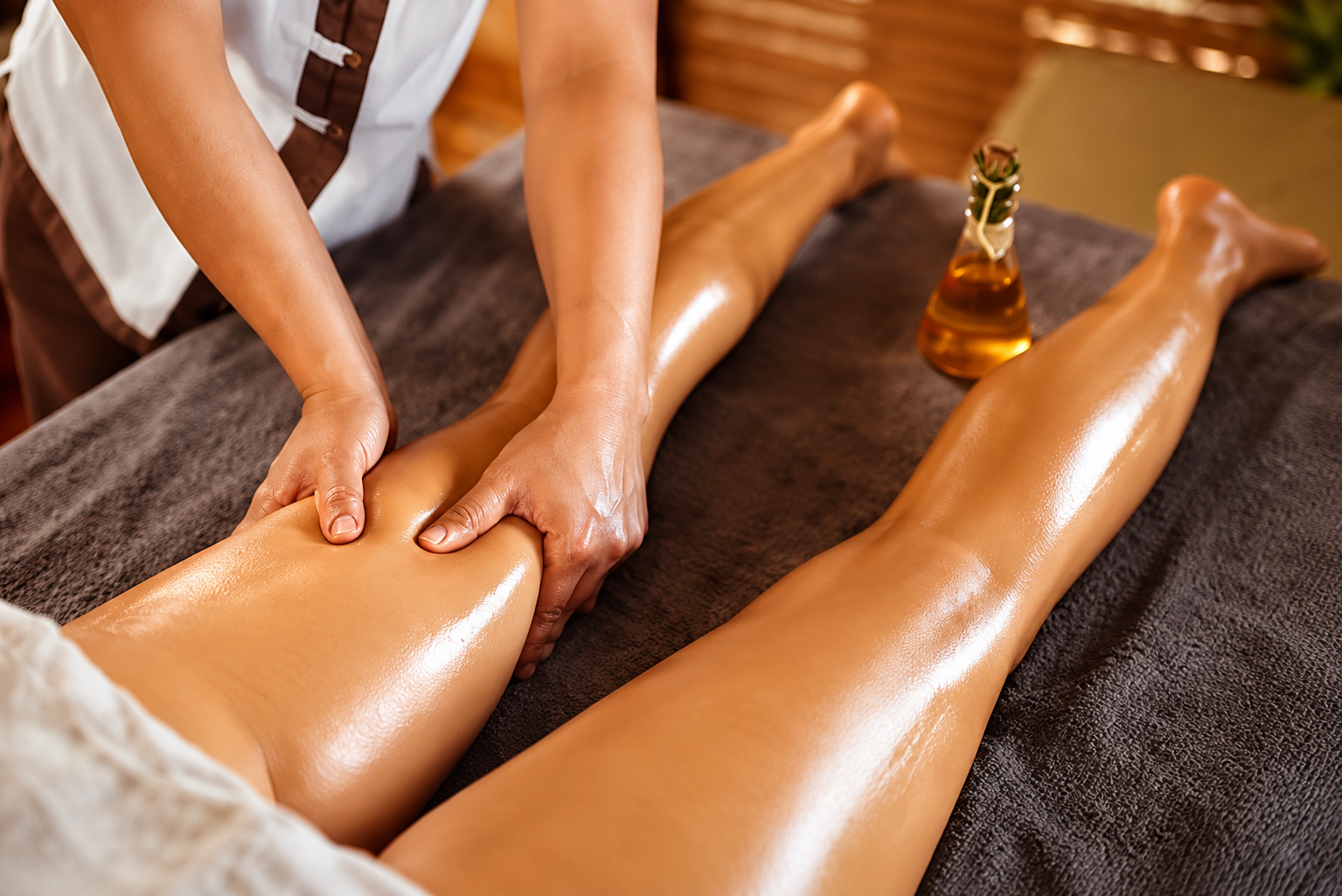 Una massaggiatrice spa fa un massaggio a una cliente su un lettino, usando olio caldo.
