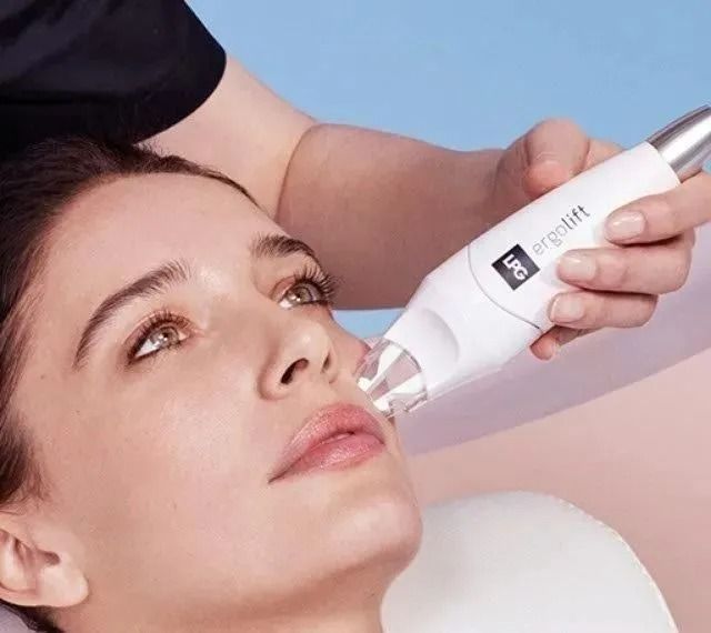 Una donna riceve un trattamento viso con un dispositivo portatile in un ambiente spa.