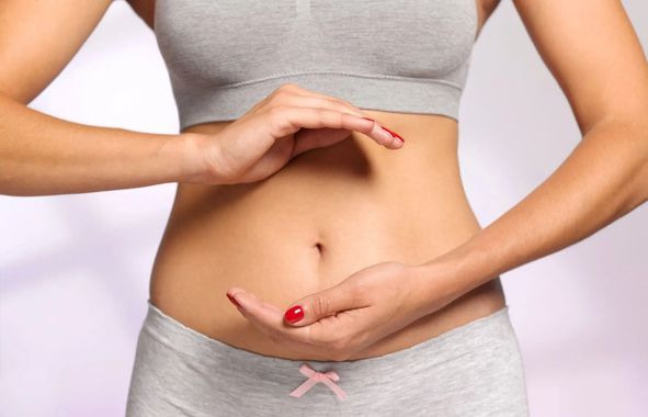 Persona che misura il girovita con le mani, con indosso biancheria intima grigia, su sfondo bianco.