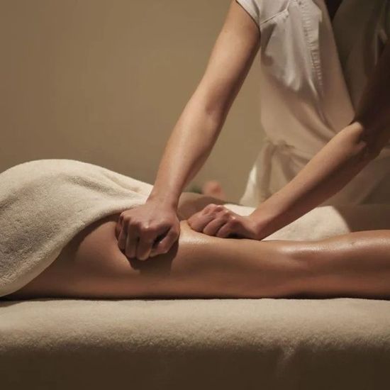 In una tranquilla spa, un massaggiatore preme la gamba di un cliente su un lettino da massaggio beige.