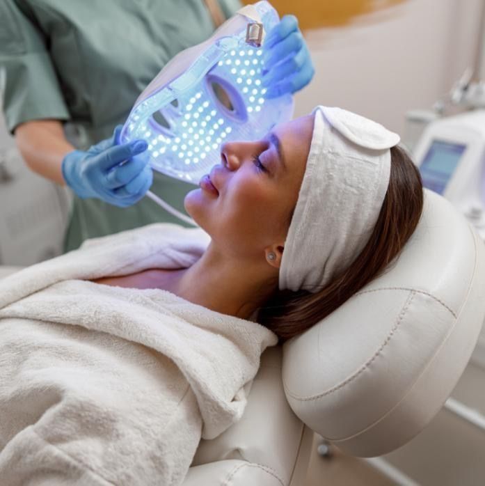 Una donna riceve un trattamento viso con LED blu mentre è sdraiata su una poltrona da spa.