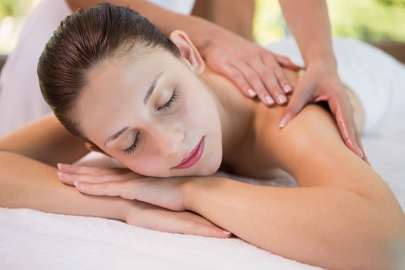 Una donna riceve un massaggio alle spalle mentre è sdraiata a pancia in giù su un lettino da spa.