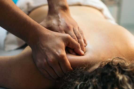 Un massaggiatore massaggia il collo e le spalle di un cliente durante un trattamento in una spa.