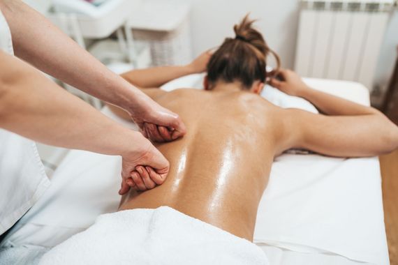 Massaggiatrice che impasta la schiena di un cliente durante un trattamento in una spa.