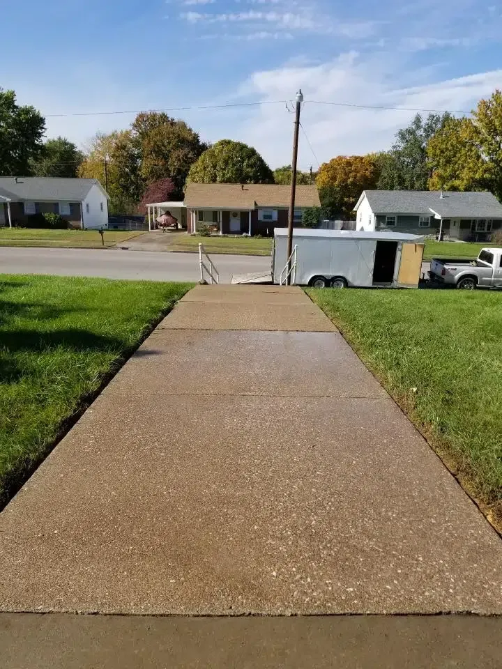 Concrete sidewalk leading to street in residential neighborhood with houses and trailer.