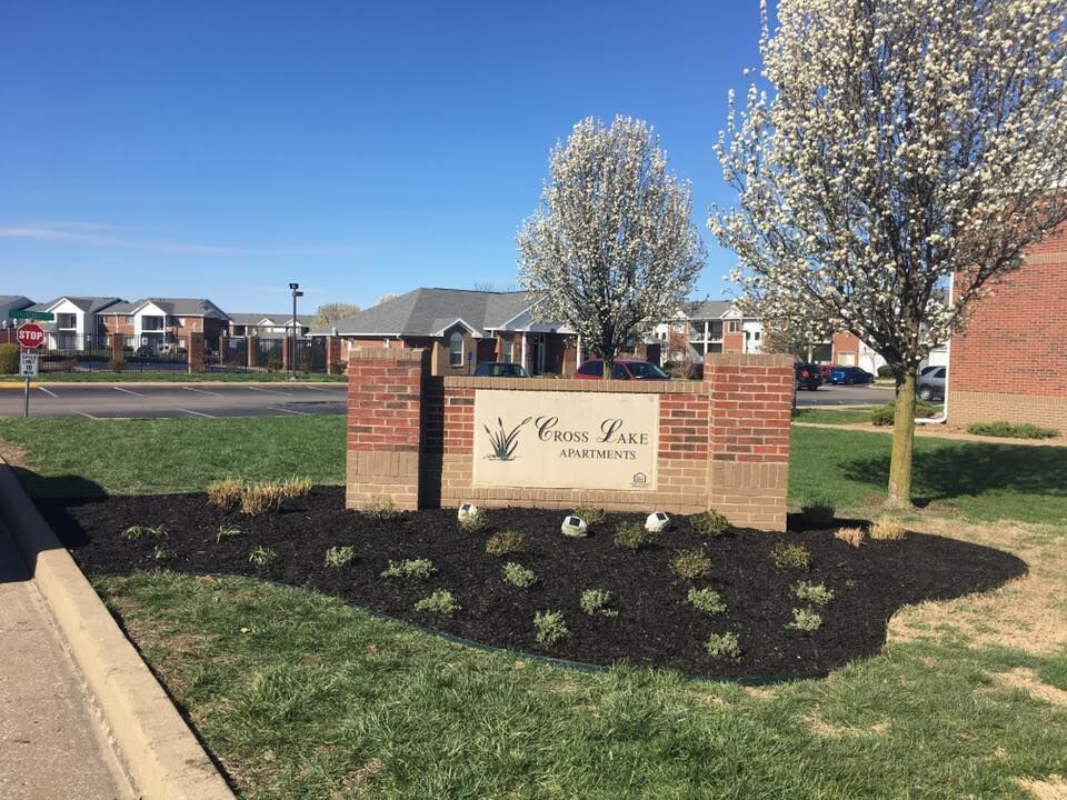 Sign for Cross Park Apple Heights Apartments with brick columns, grass, and newly mulched flower beds.