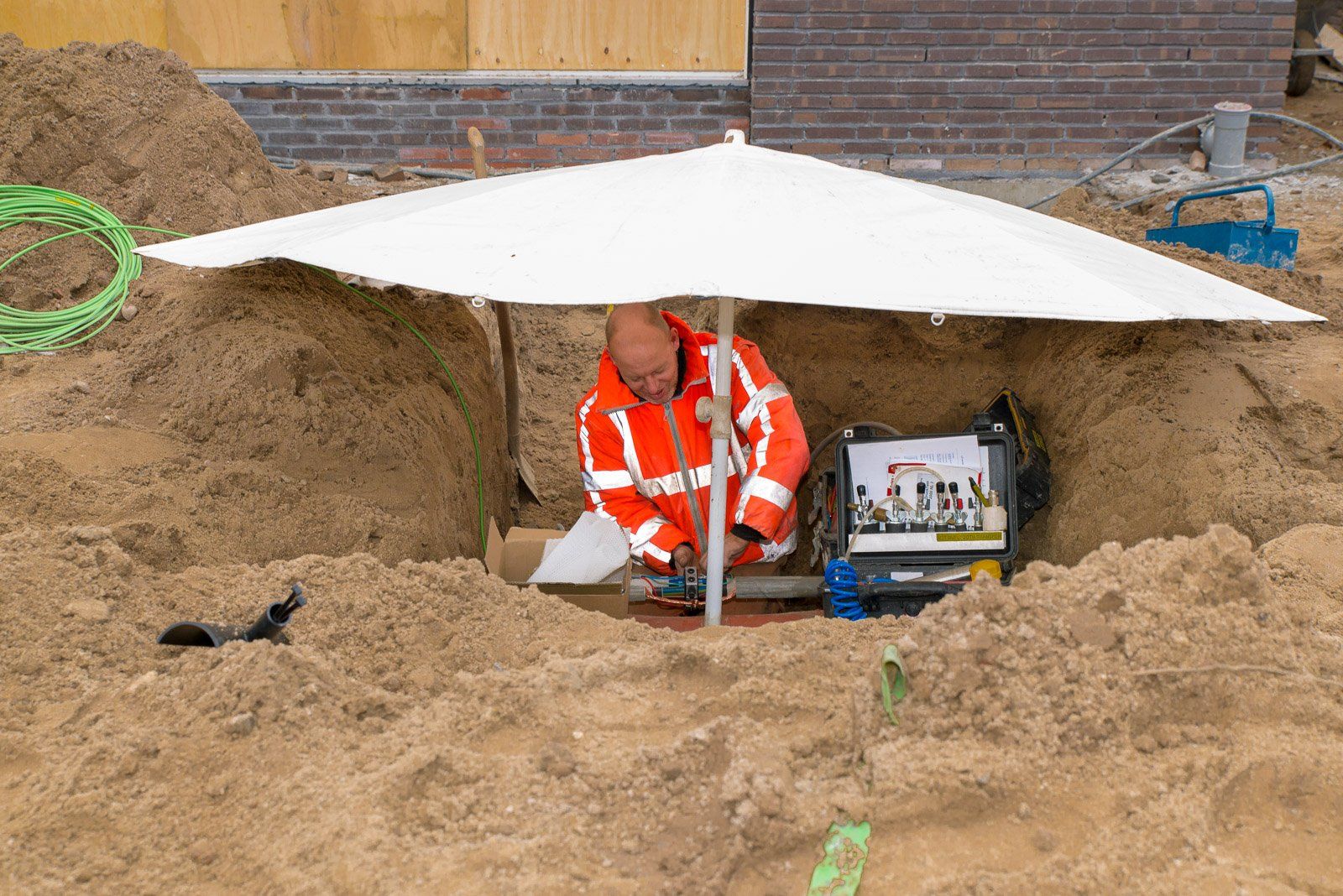 Portfolio Walter Frisart FOTOwerk Bouwfotograaf, Bouwplaatsfotograaf en projectfotograaf: Ruwbouw Knarrenhof Nutsmedewerker onder grote paraplu voor Trebbe, Knarrenhof en Inbo
