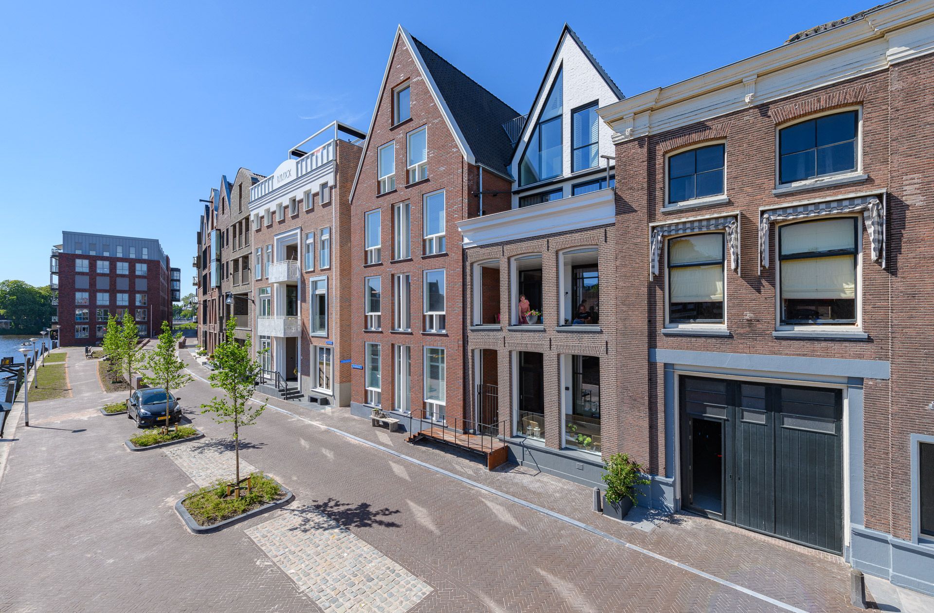 Een rij bakstenen gebouwen met uiteenlopende architectonische stijlen langs een straat met kinderkopjes.